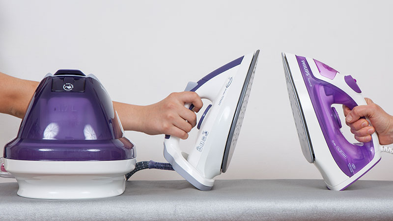 duas mãos levantam dois ferros de engomar em cima de uma tábua de passar a ferro